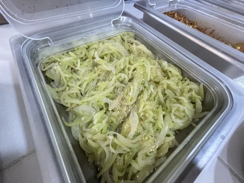 필리핀 클락 벨라(BELA) 어학원 식당 식사로, 배식통에 참깨를 뿌린 오이·양파 채무침이 담겨 있는 모습입니다.