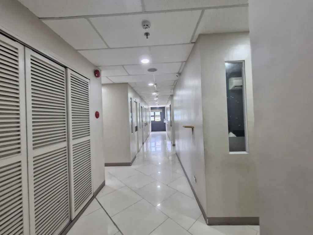 필리핀 세부 셀라(CELLA) 유니캠퍼스 어학원 기숙사 복도로, 왼쪽 통풍구형 여닫이문과 화재경보기가 설치된 복도를 따라 객실 문들이 이어져 있습니다.