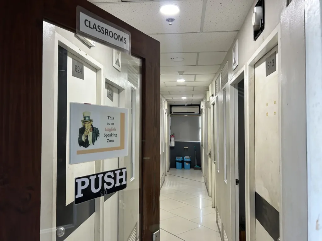 필리핀 세부 셀라(CELLA) 유니캠퍼스 어학원 강의실 복도로, 624호 CLASSROOMS 팻말과 영어 사용 안내 포스터가 붙은 강의실 출입문입니다.
