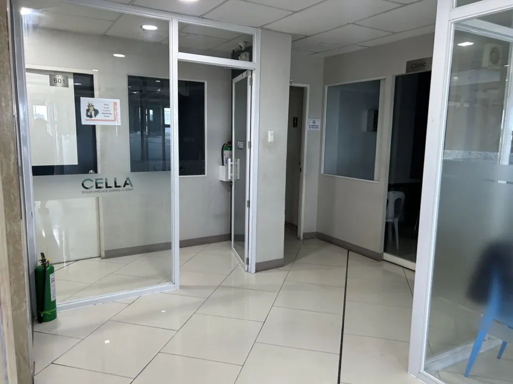 필리핀 세부 셀라(CELLA) 유니캠퍼스 어학원 강의실 복도로, 601호 유리문에 CELLA 로고와 영어 사용 안내문이 붙은 강의동 입구입니다.