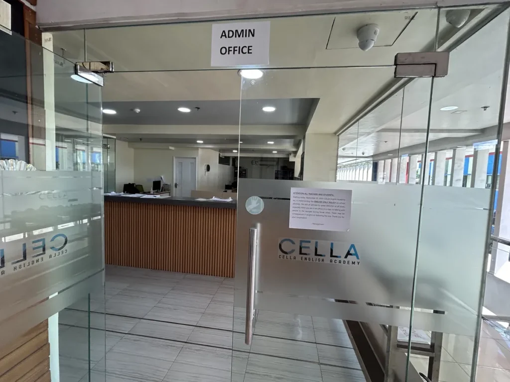 필리핀 세부 셀라(CELLA) 유니캠퍼스 어학원 부대시설 오피스로, 'ADMIN OFFICE' 표지 붙은 유리문 너머 프런트 데스크가 보이는 입구입니다.