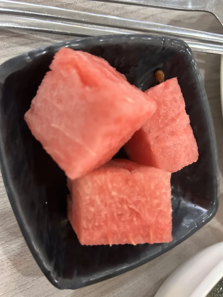 필리핀 세부 셀라(CELLA) 유니캠퍼스 어학원 학생식당 식사로, 씨앗이 보이는 수박 세 조각이 검은 사각 접시에 소담히 담긴 모습입니다.