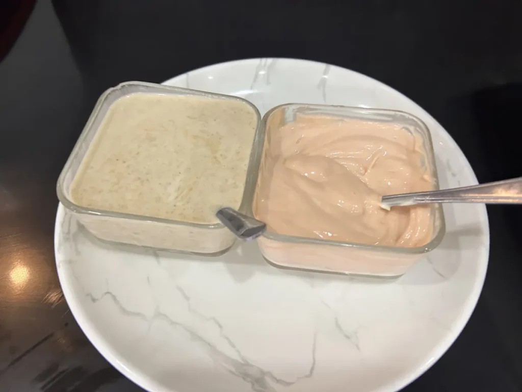 필리핀 세부 셀라(CELLA) 유니캠퍼스 어학원 학생식당 식사로, 베이지색과 분홍색 소스 두 종류가 유리 용기에 담겨 스푼과 함께 놓인 모습입니다.