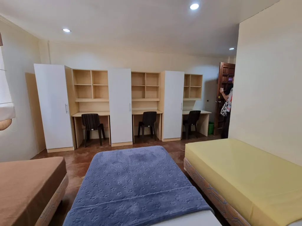 필리핀 세부 CG 바닐라드 어학원 기숙사 3인실로, 흰색 옷장과 책장·책상이 결합된 3세트 가구가 벽면을 따라 나란히 배치된 스터디 공간입니다.
