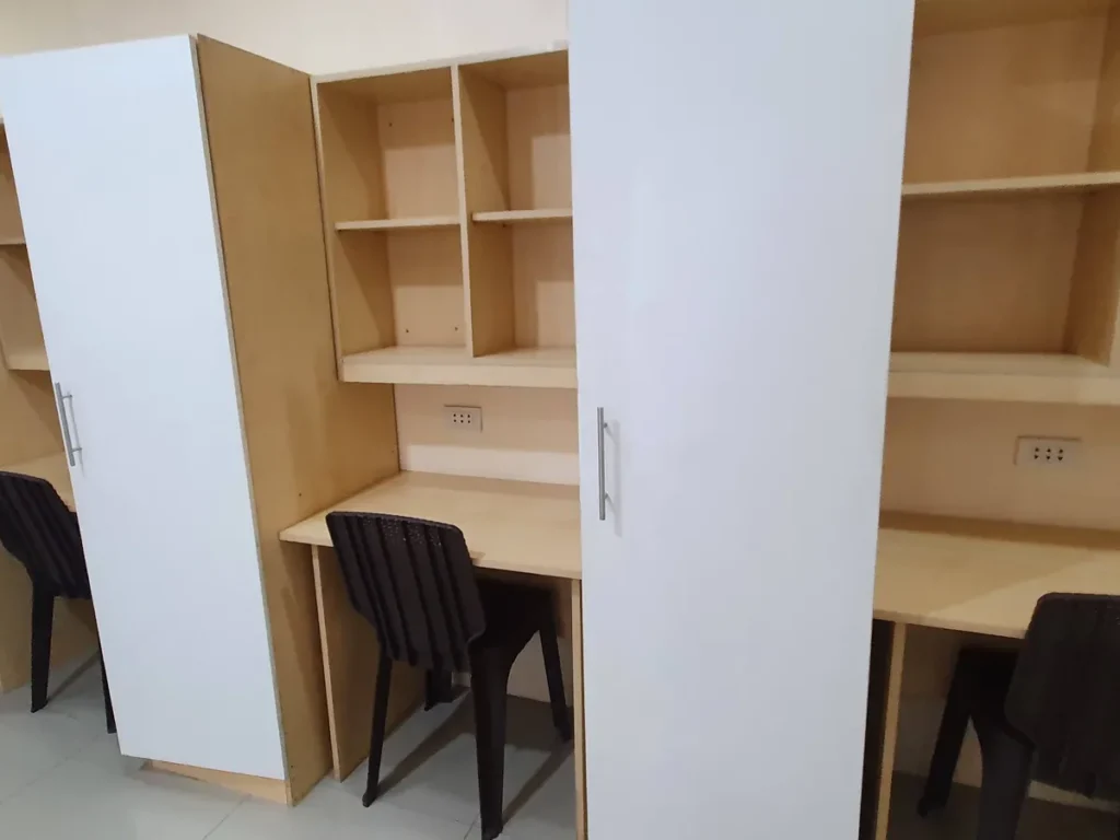 필리핀 세부 CG 바닐라드 어학원 기숙사 4인실로, 흰색 옷장 문 사이 콘센트와 선반을 갖춘 책상이 자리한 가구 디테일입니다.
