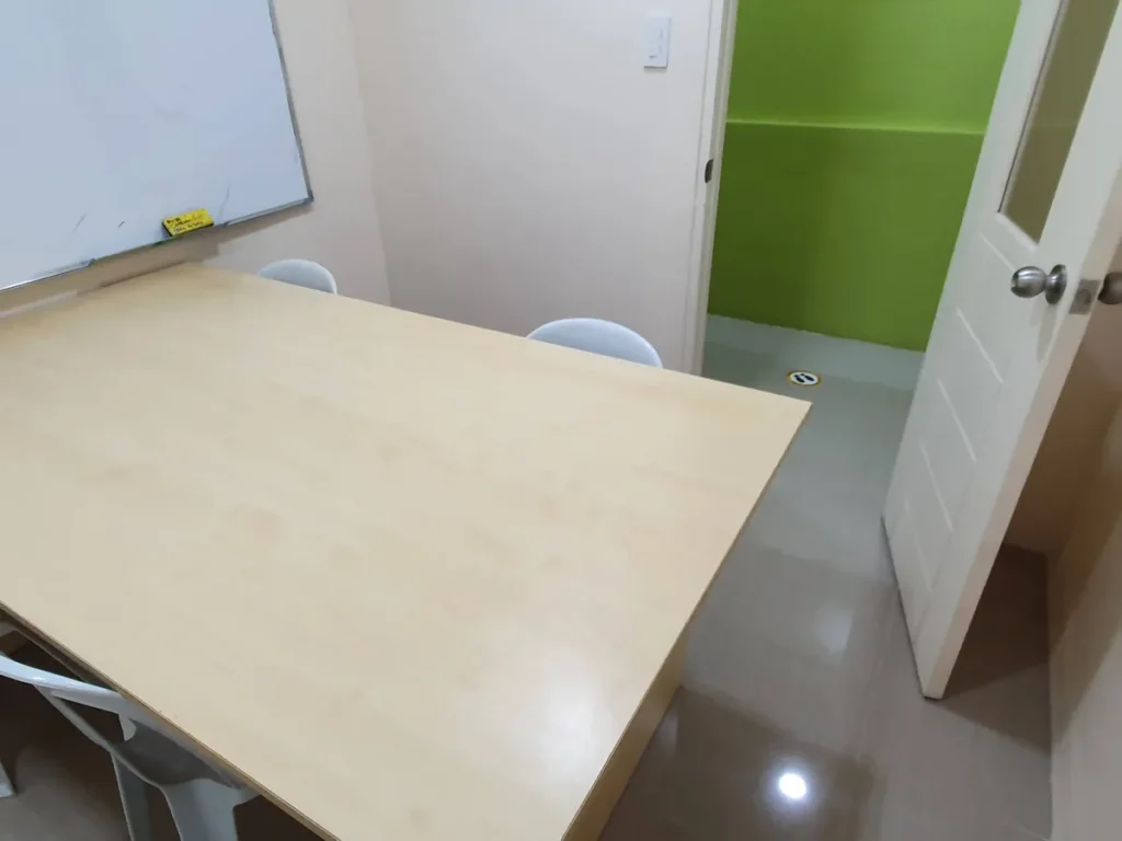 필리핀 세부 CG 바닐라드 어학원 그룹 강의실로, 원목 책상과 의자가 놓이고 열린 문 너머로 연두색 벽의 작은 강의실이 이어지는 구성입니다.