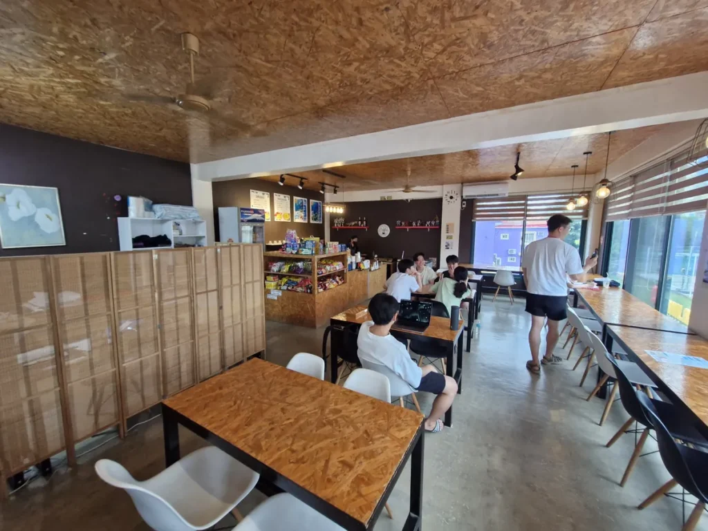 필리핀 세부 CG 바닐라드 어학원 매점으로, 우드 천장과 파티션 안쪽 좌석에 학생들이 앉아있고 뒤편 카운터에 메뉴판과 진열대가 보이는 매점 전경입니다.