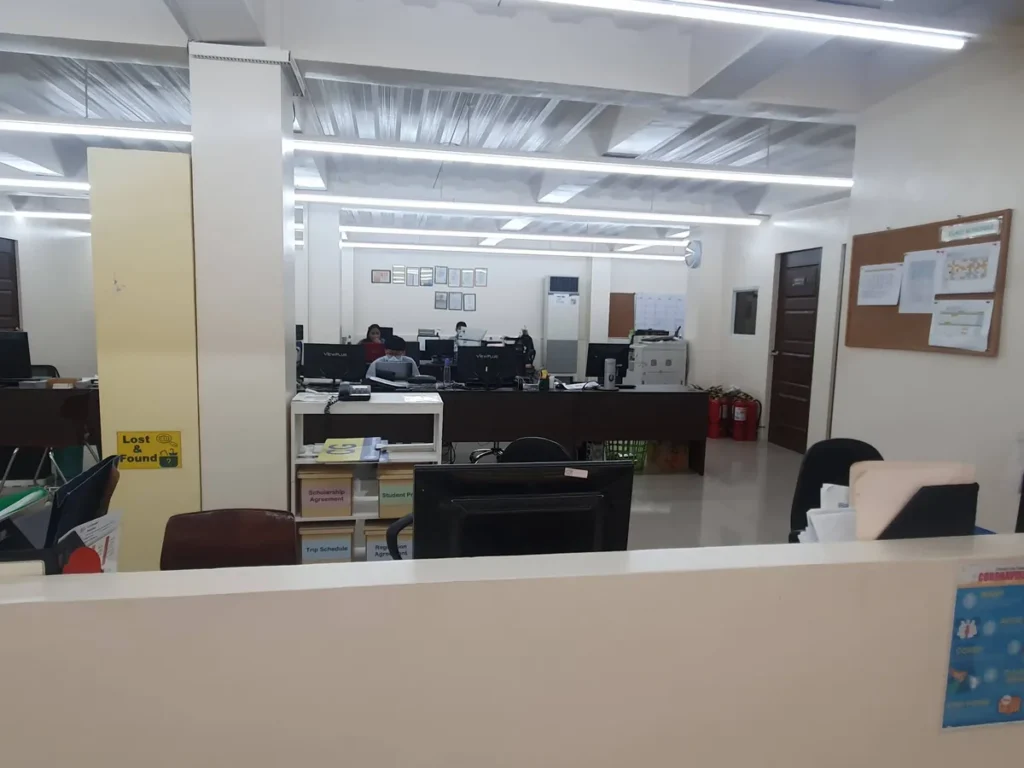 필리핀 세부 CG 바닐라드 어학원 부대시설 오피스로, 직원이 업무 중인 책상과 장학금·등록 서류함, 소화기가 놓인 사무 공간입니다.