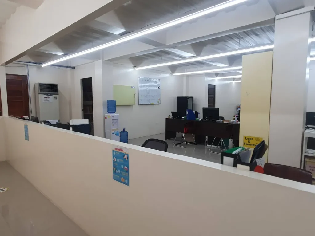 필리핀 세부 CG 바닐라드 어학원 부대시설 오피스로, 냉온수기와 화이트보드, 갈색 사무 책상이 놓인 사무실 안쪽 모습입니다.