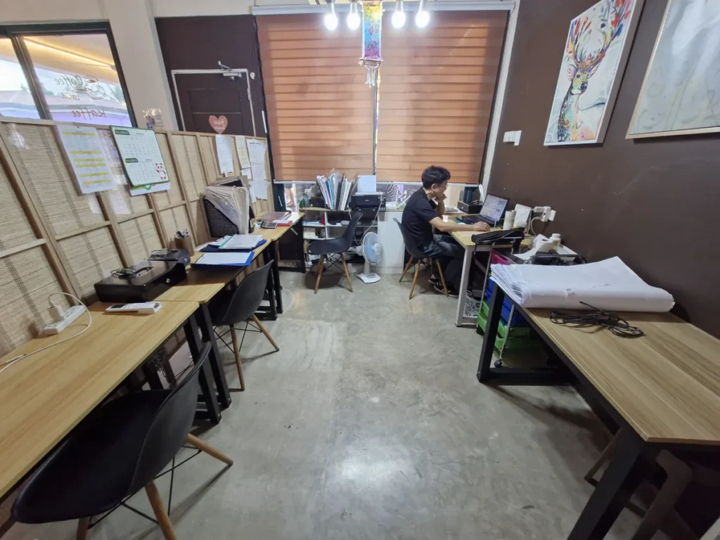 필리핀 세부 CG 바닐라드 어학원 부대시설 오피스로, 커피숍 창문 옆 원목 책상에서 직원이 노트북으로 업무를 보는 별도 사무공간입니다.
