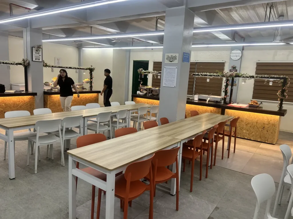 필리핀 세부 CG 바닐라드 어학원 식당으로, 생화 장식 아치 아래 배식 카운터에서 직원들이 준비 중인 저녁 시간대 모습입니다.