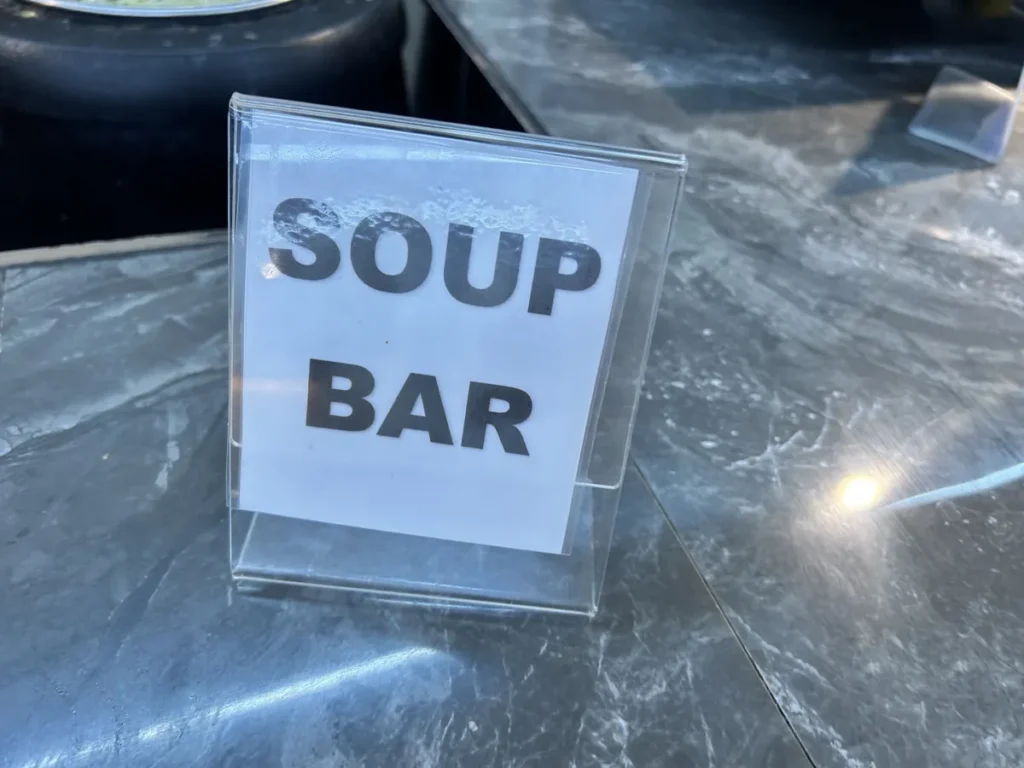 필리핀 세부 CG 바닐라드 어학원 식당으로, 조리대 위에 놓인 투명 스탠드의 Soup Bar(수프 바) 안내판입니다.