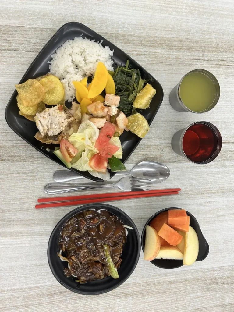 필리핀 세부 CG 바닐라드 어학원 식당 식사로, 밥과 반찬 접시 옆으로 음료 두 잔과 나물·과일이 담긴 작은 그릇들이 놓여 있습니다.