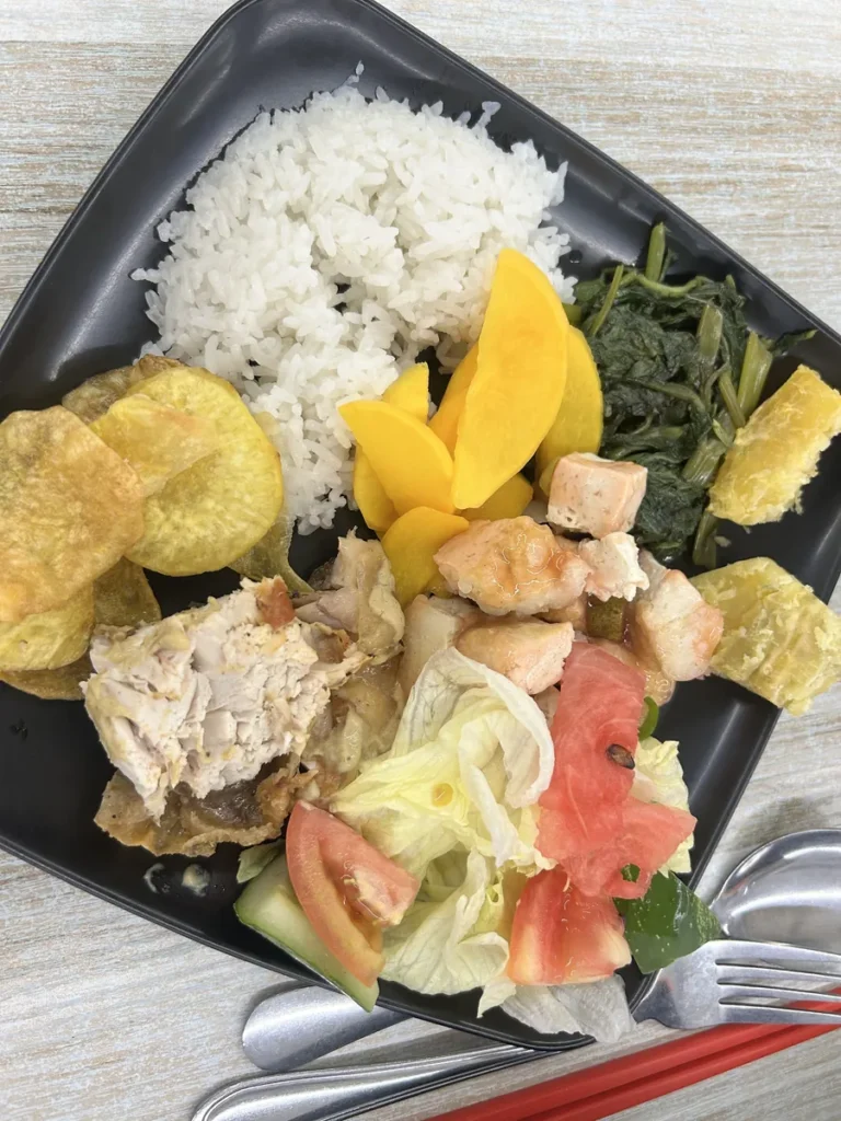 필리핀 세부 CG 바닐라드 어학원 식당 식사로, 검은 사각 접시에 흰쌀밥·감자칩·망고·나물·닭고기·두부조림이 함께 담겨 있습니다.