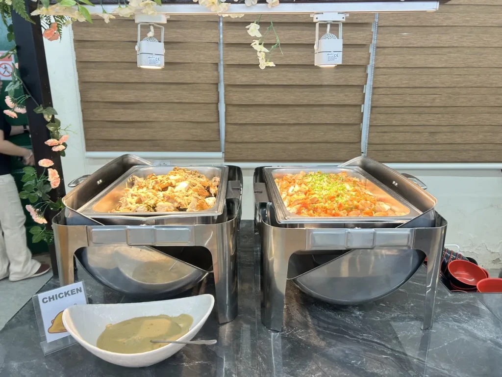 필리핀 세부 CG 바닐라드 어학원 식당 식사로, CHICKEN 팻말이 놓인 뷔페 라인에 치킨 조림과 야채 소스 요리 찜통이 놓여 있습니다.