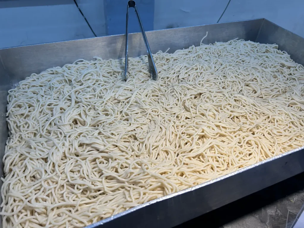 필리핀 세부 CG 바닐라드 어학원 식당 식사로, 집게가 꽂힌 철제 트레이에 부드럽게 삶아진 면발이 가득 채워져 있는 모습을 가까이서 보여줍니다.