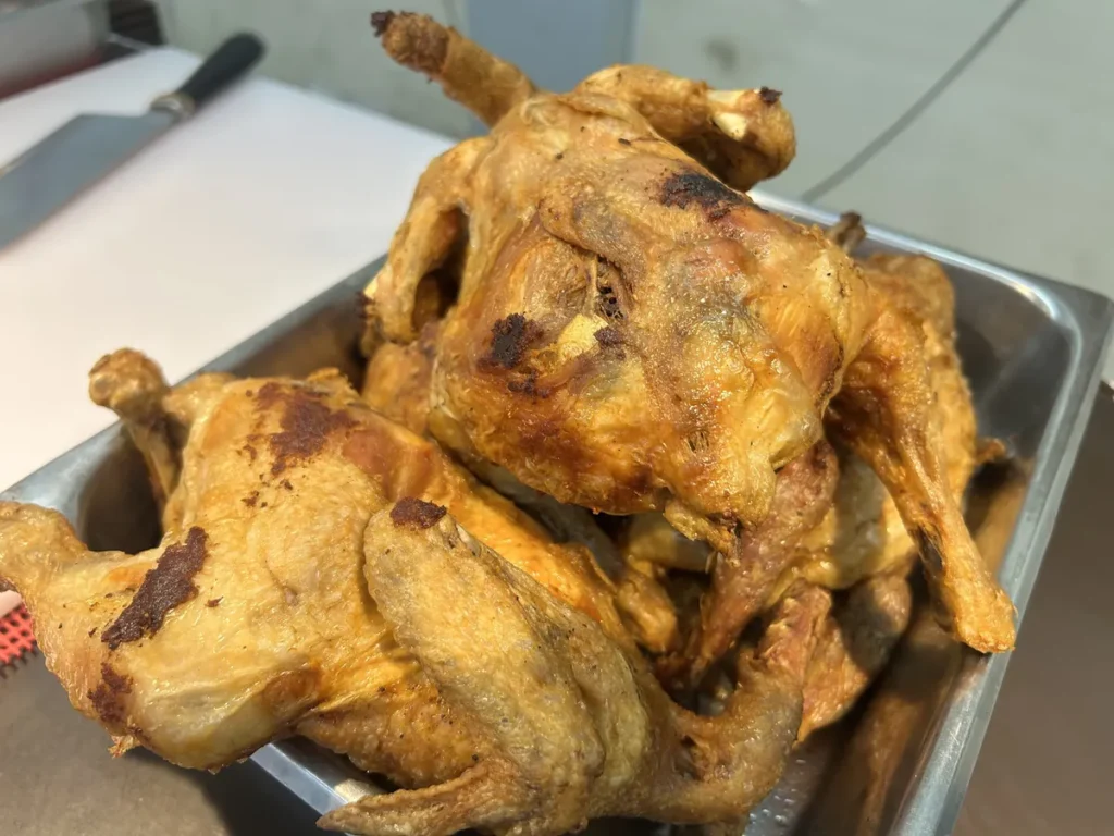 필리핀 세부 CG 바닐라드 어학원 식당 식사로, 노릇하게 구워진 통닭 여러 마리가 스테인리스 트레이에 겹겹이 담겨 있습니다.