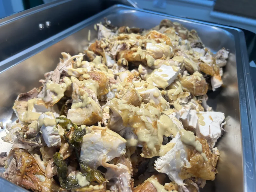 필리핀 세부 CG 바닐라드 어학원 식당 식사로, 결대로 찢어진 구운 닭고기 위에 크림 소스가 듬뿍 뿌려진 채 철제 트레이에 담겨 있습니다.
