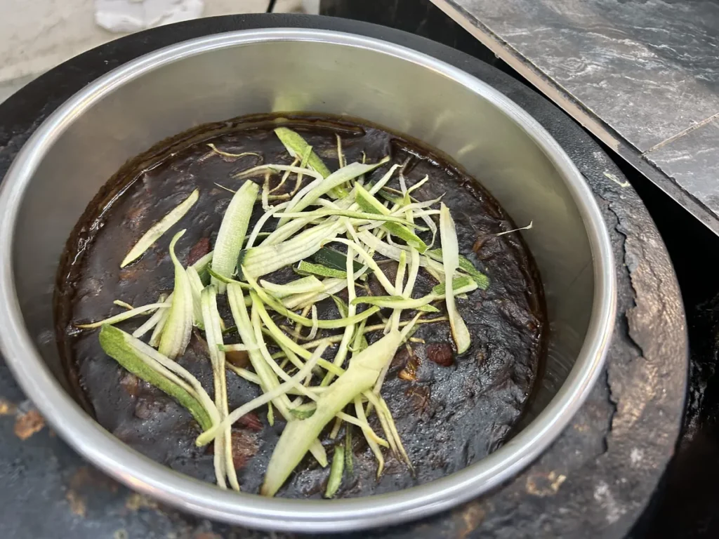 필리핀 세부 CG 바닐라드 어학원 식당 식사로, 진한 갈색 소스가 담긴 철제 볼 위에 채썬 오이와 청경채가 고명으로 올라가 있습니다.