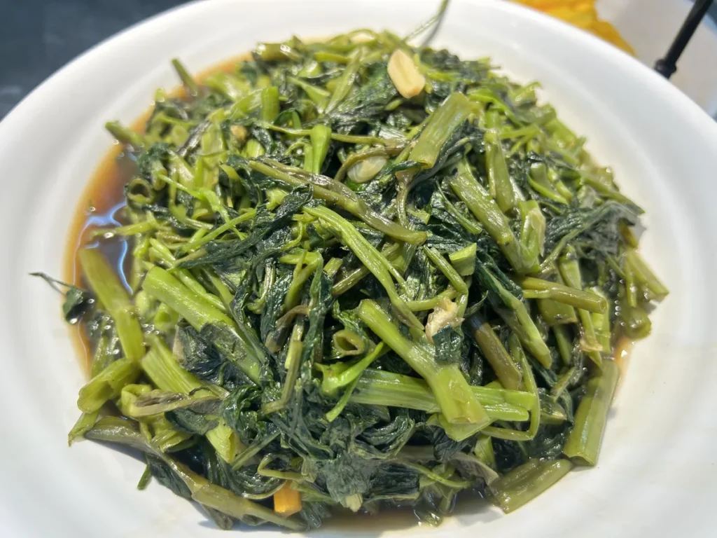 필리핀 세부 CG 바닐라드 어학원 식당 식사로, 흰 접시에 마늘과 간장 소스로 볶은 청경채 나물이 수북하게 담겨 있는 모습을 가까이서 보여줍니다.
