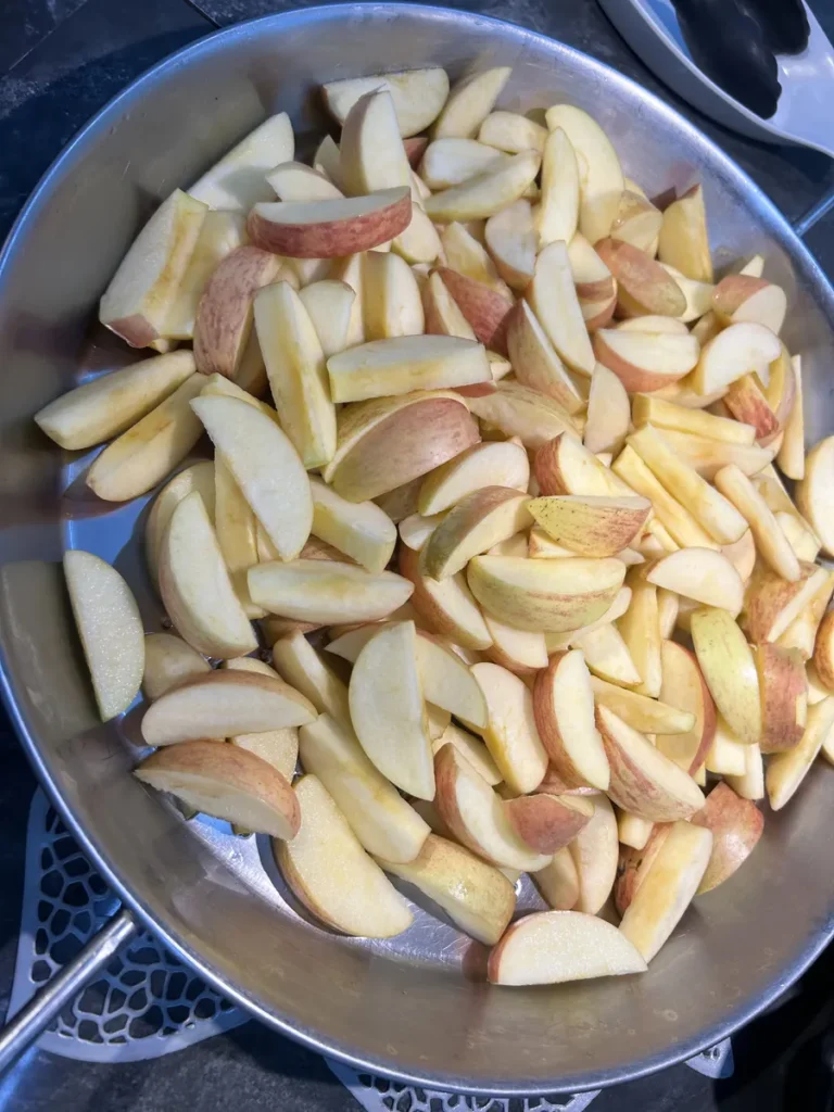 필리핀 세부 CG 바닐라드 어학원 식당 식사로, 큰 철제 팬에 껍질째 썬 사과 조각이 수북하게 담겨 있는 모습을 가까이서 보여줍니다.