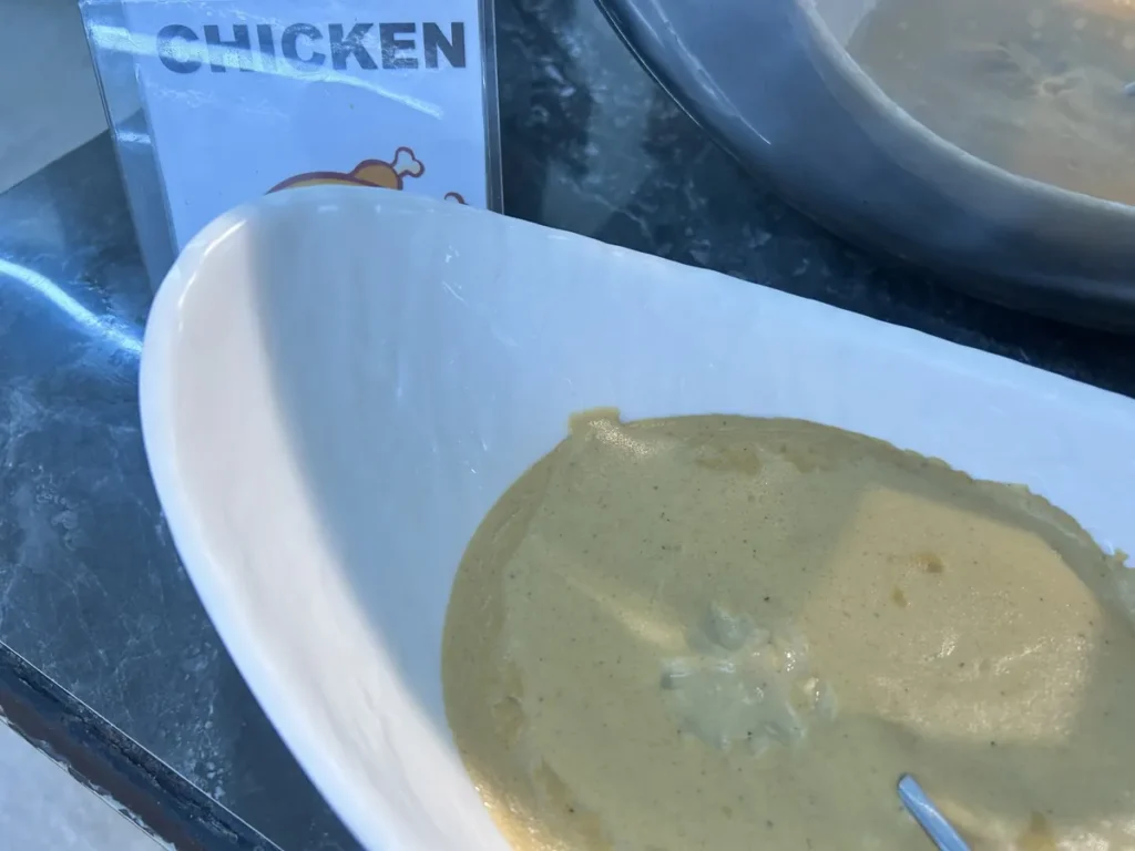 필리핀 세부 CG 바닐라드 어학원 식당 식사로, CHICKEN 팻말 옆에 부드러운 크림 소스가 담긴 흰 그릇이 놓여 있는 모습을 가까이서 보여줍니다.