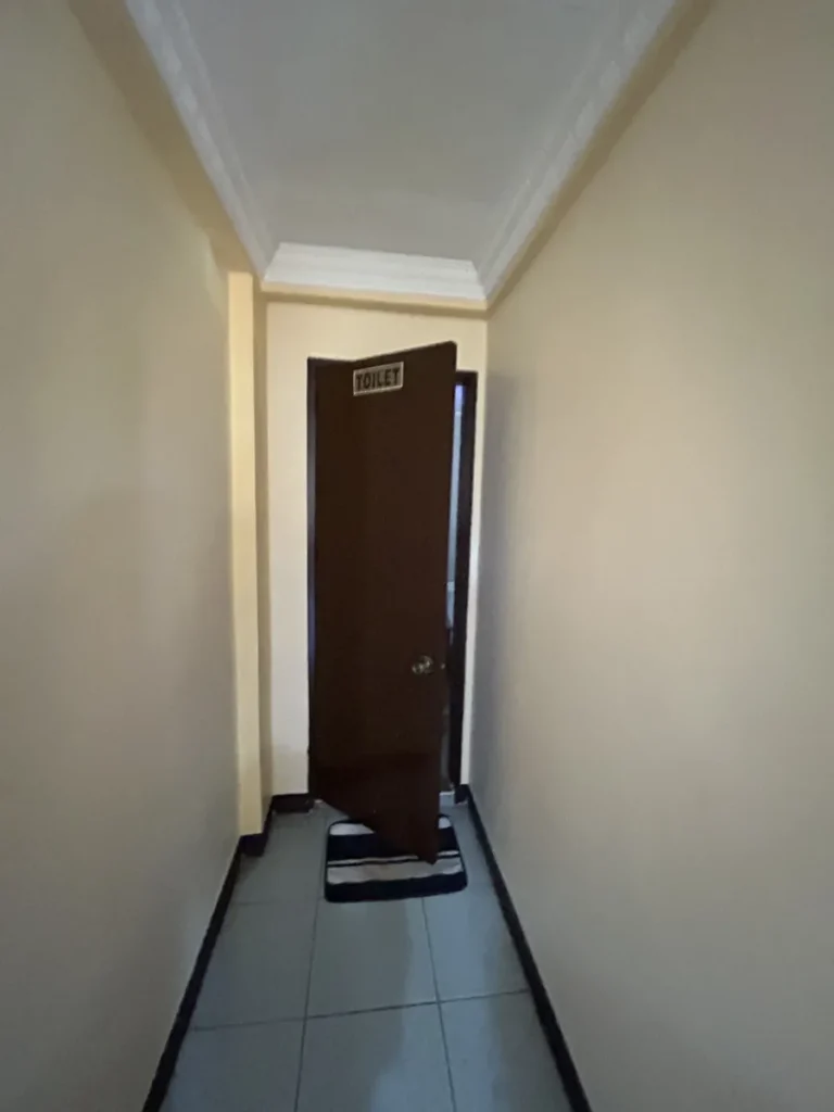 필리핀 세부 CG 스파르타 어학원 기숙사 복도로, TOILET 팻말이 붙은 문이 살짝 열려 있는 좁은 화장실 입구 통로입니다.