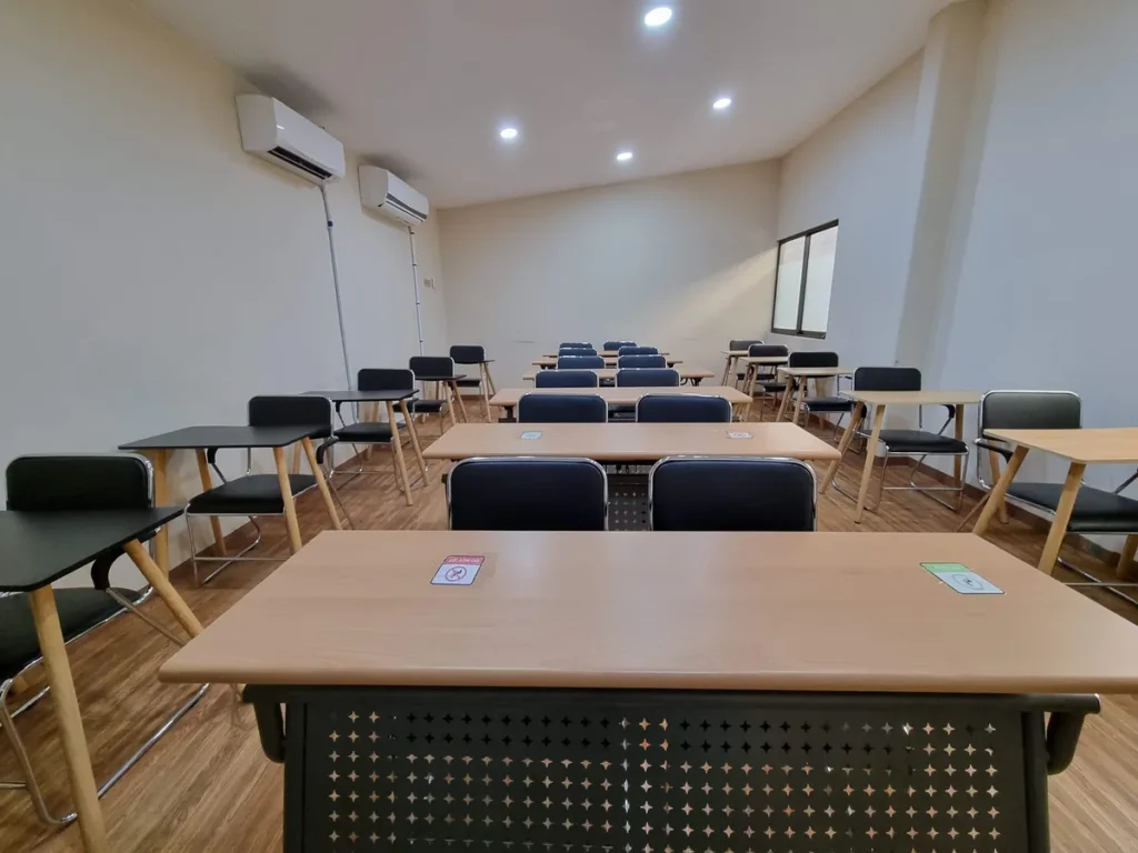 필리핀 세부 CG 스파르타 어학원 강의실 그룹반으로, 벽면에 에어컨 두 대가 설치된 넓은 강의실에 검정 의자와 원목 책상이 줄지어 있습니다.