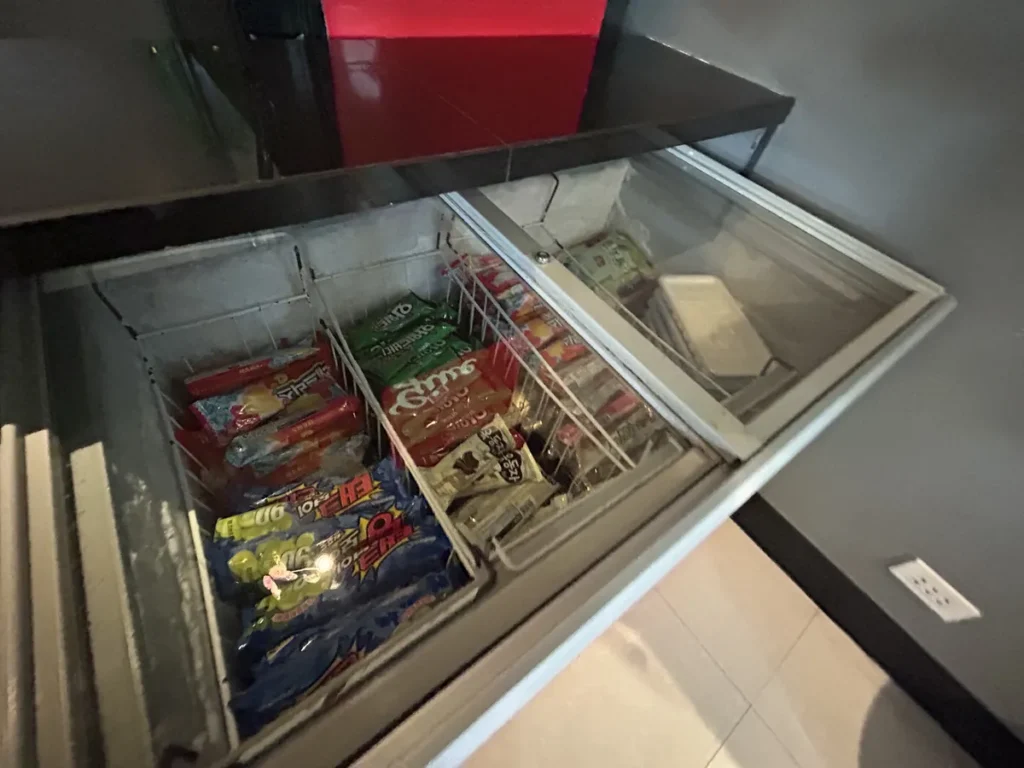 필리핀 세부 JJES 어학원 부대시설 매점으로, 투명 유리 뚜껑 아래 아이스크림과 빙과류가 칸칸이 나뉜 바구니에 담긴 냉동고 내부 모습입니다.