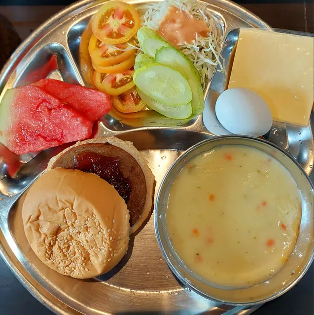 필리핀 세부 JJES 어학원 학생식당 식사로, 수박과 토마토·오이 샐러드, 치즈·삶은 달걀에 햄버거와 크림수프를 곁들인 식판입니다.