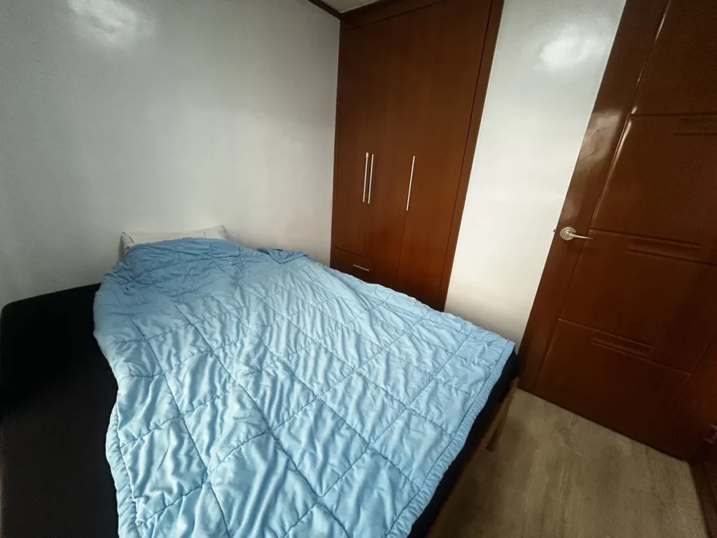 필리핀 바기오 웨일즈(WALES) 어학원 기숙사 1인실 공유형(베란다)로, 하늘색 침구 침대 옆 원목 옷장이 놓인 방입니다.