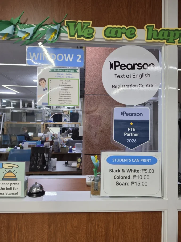 필리핀 바기오 웨일즈(WALES) 어학원 부대시설 오피스·안내판으로, Window 2 창구에 Pearson 등록 안내와 프린트 요금표가 붙은 모습입니다.
