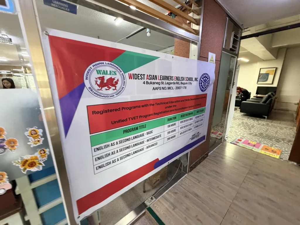 필리핀 바기오 웨일즈(WALES) 어학원 부대시설 오피스·안내판으로, WALES 정식 등록증과 TESDA 프로그램 안내 배너입니다.