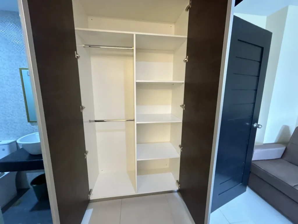 필리핀 세부 CIJ 어학원 외부 기숙사 3인실로, 양문을 연 붙박이 옷장 안에 옷걸이 봉 2개와 선반 여러 칸이 있는 수납공간입니다.