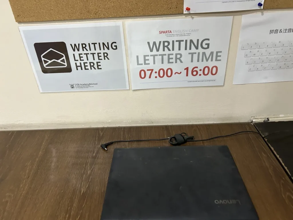 필리핀 세부 CIJ 어학원 안내판으로, 편지 쓰기 공간과 07:00~16:00 이용 시간 안내문 아래 노트북이 놓인 책상입니다.
