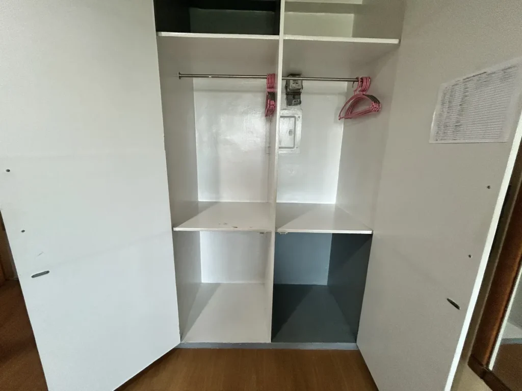 필리핀 세부 시필스(CPILS) 어학원 2인실 프리미엄룸 수납장으로, 옷걸이가 걸린 행거와 위아래 칸막이 선반으로 나뉜 붙박이장 내부입니다.