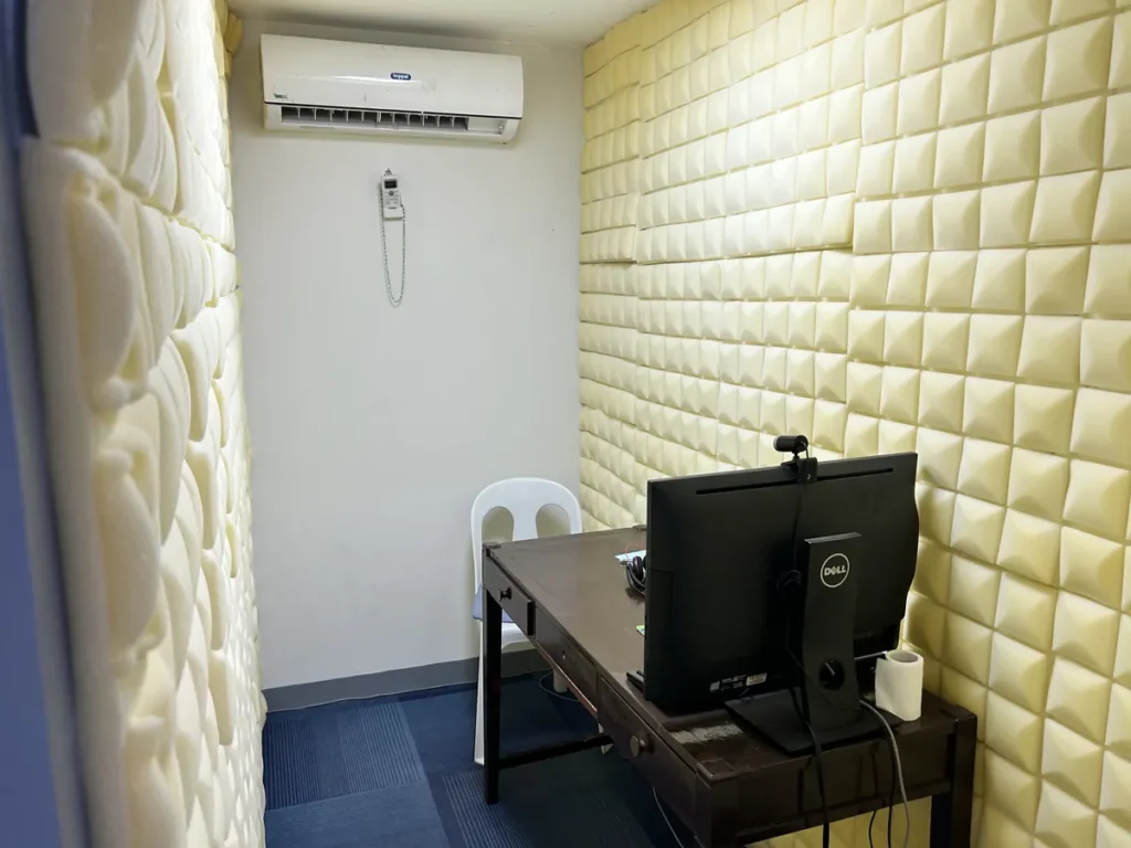필리핀 세부 시필스(CPILS) 어학원 아이엘츠 시험장으로, 양쪽 벽에 흡음재를 붙이고 책상 위에 웹캠 달린 모니터를 둔 스피킹 시험실 내부입니다.