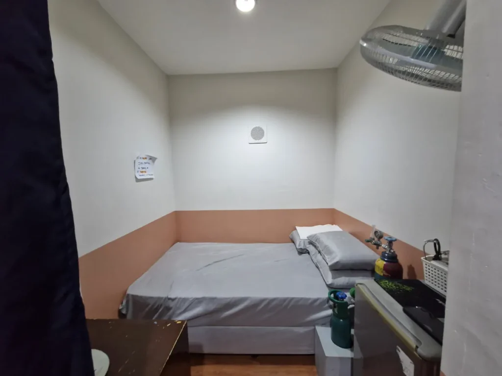 필리핀 세부 시필스(CPILS) 어학원 클리닉으로, 커튼 안쪽 작은 방에 침상과 베개, 산소통과 벽걸이 선풍기가 갖춰진 휴식실입니다.