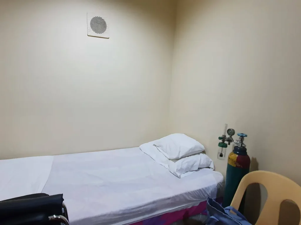 필리핀 세부 시필스(CPILS) 어학원 클리닉으로, 흰 시트와 베개가 놓인 침상 옆에 산소통과 의자가 준비된 모습입니다.