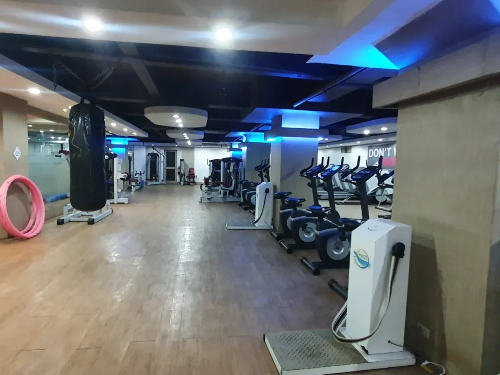필리핀 세부 시필스(CPILS) 어학원 헬스장으로, 나무 바닥 위에 샌드백과 실내 자전거·웨이트 머신이 늘어선 넓은 공간입니다.
