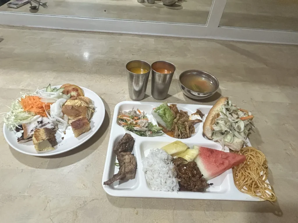 필리핀 세부 시필스(CPILS) 어학원 식당 식사 메뉴로, 칸 나뉜 식판에 밥·갈비구이·스파게티·수박·파인애플과 반미 샌드위치를 담은 한 끼입니다.